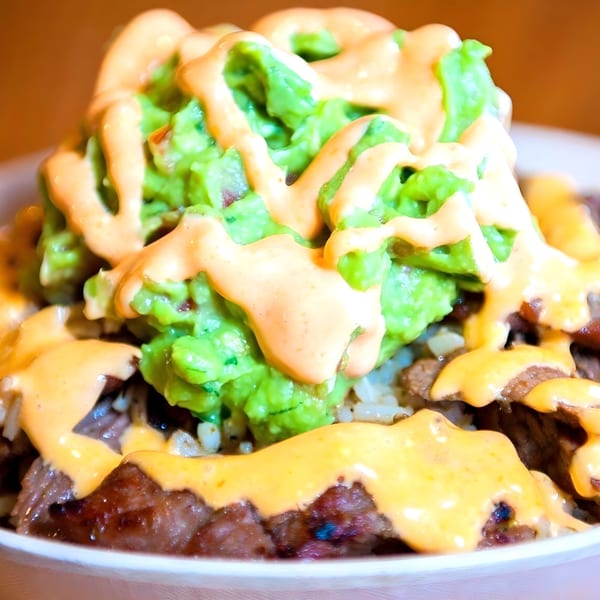 Close-up of a Westchester Taco Grill burrito bowl with steak, rice, guacamole, and orange sauce.